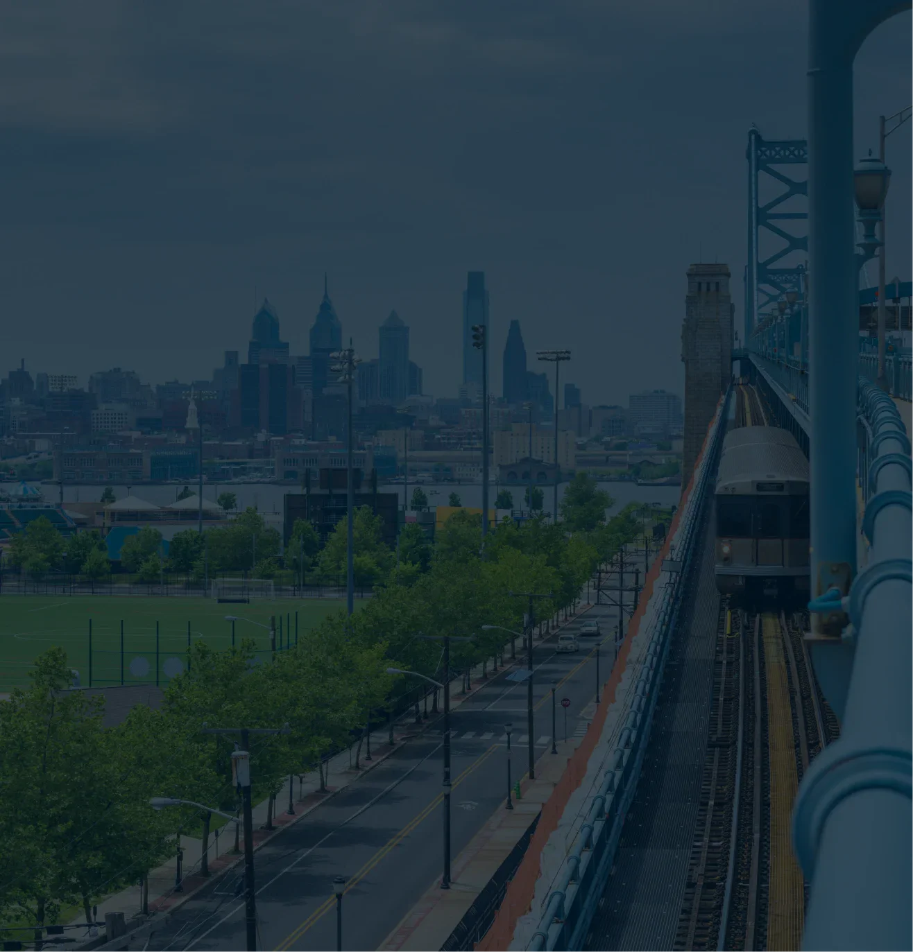 Skyline with a train on a bridge in the foreground and a cityscape in the background.