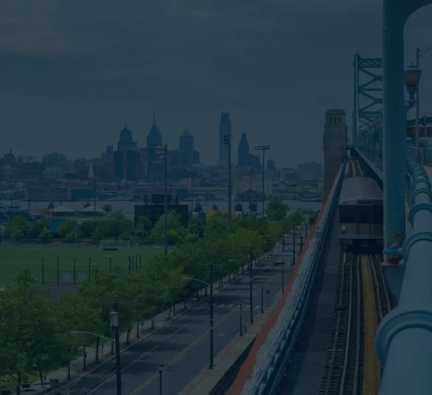 Skyline with a train on a bridge in the foreground and a cityscape in the background.